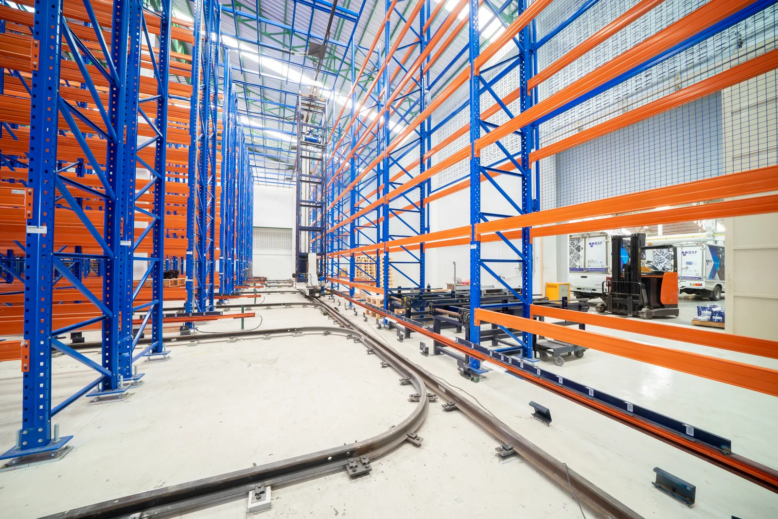 ชั้นวาง ASRS แนวสูงสีน้ำเงินส้มพร้อมรางเครนในคลังสินค้า